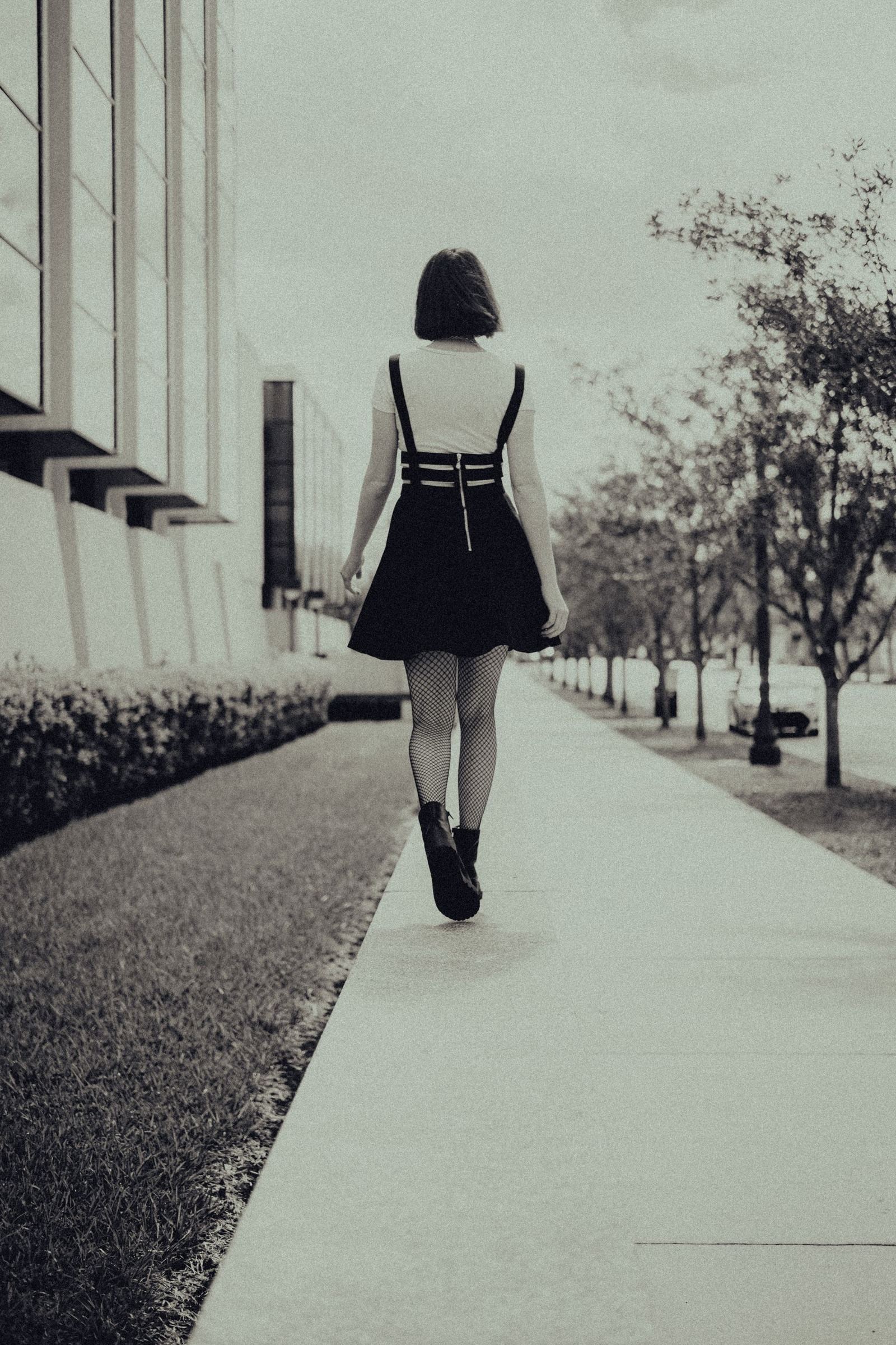 Rear view of a woman walking on a city sidewalk in a dress