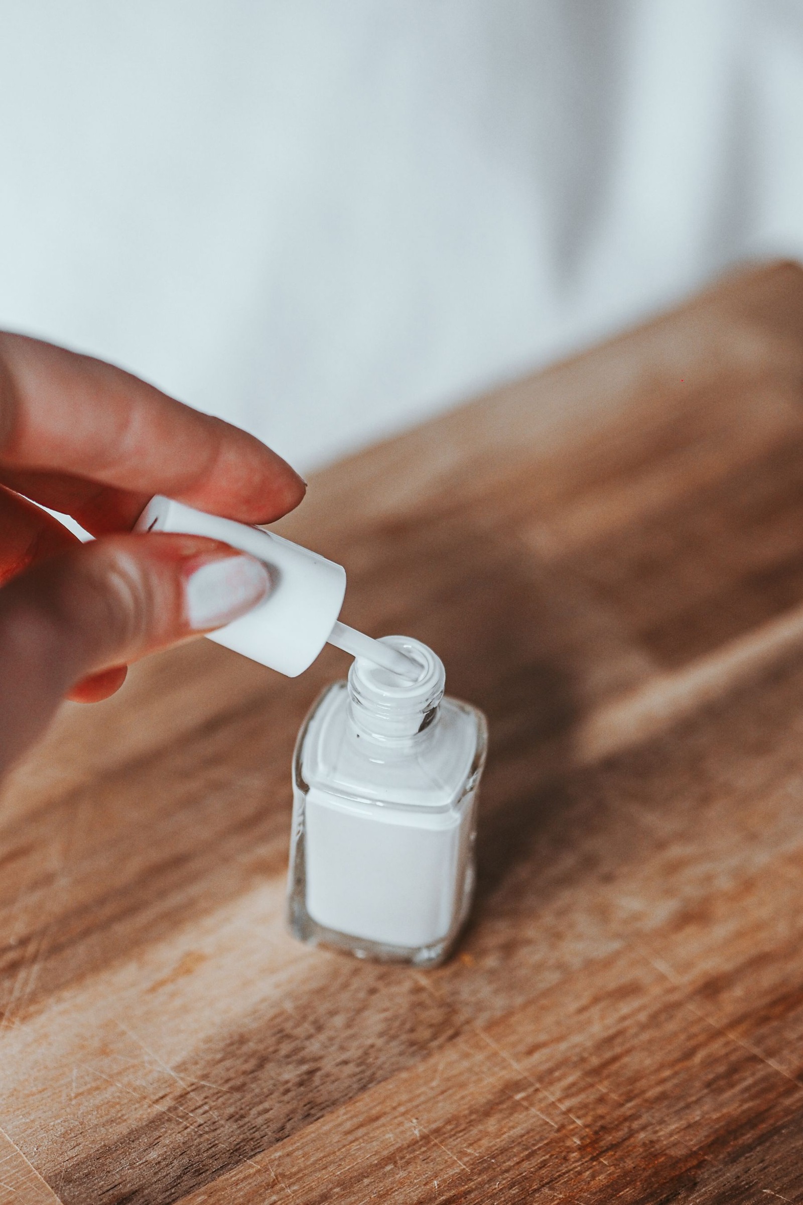 Opened white nail polish on a wooden surface