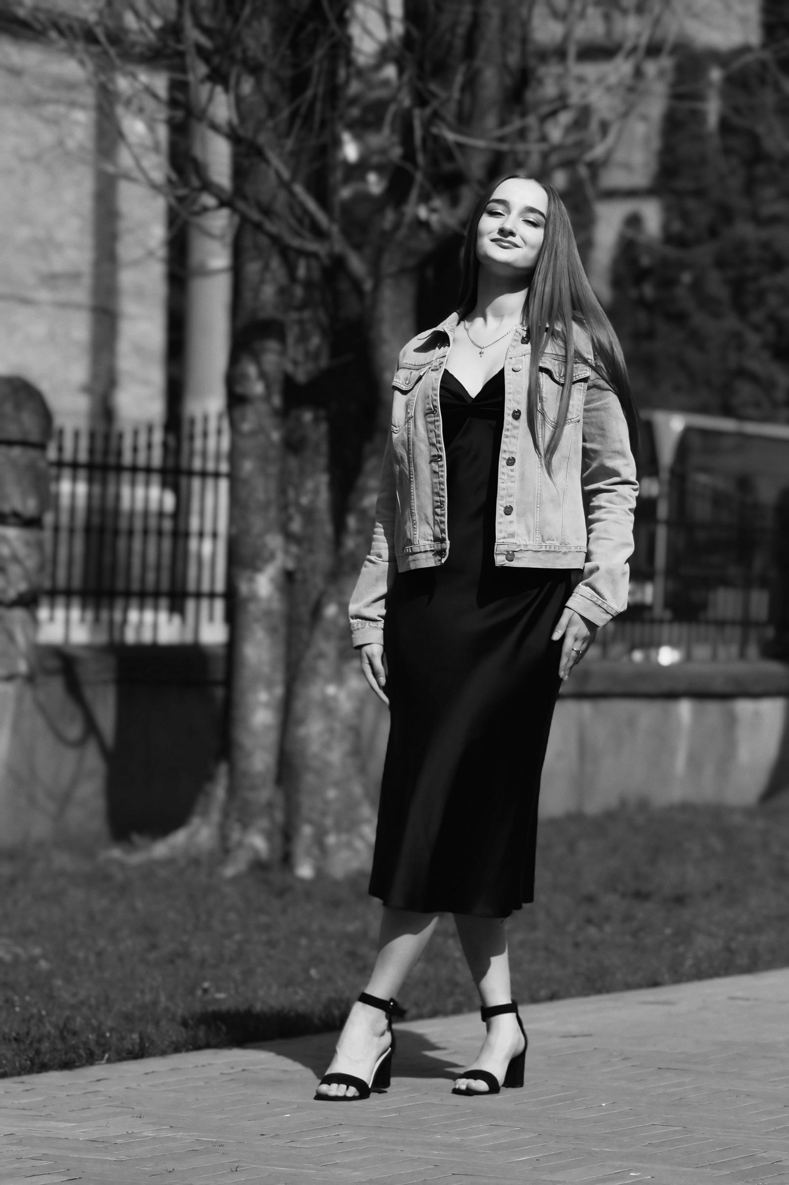 Woman wearing a black dress and denim jacket outdoors