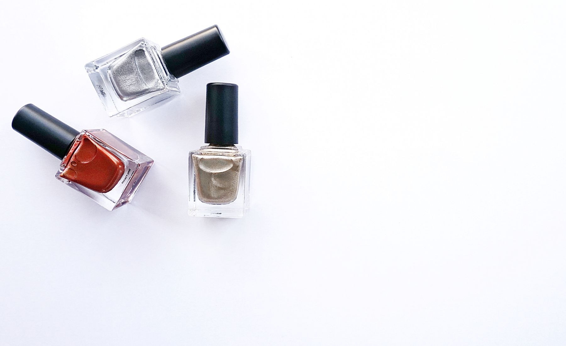 Three closed nail polish bottles arranged against white