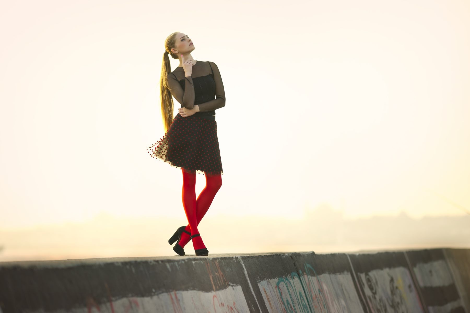 Woman wearing a black long-sleeved dress with red tights outdoors
