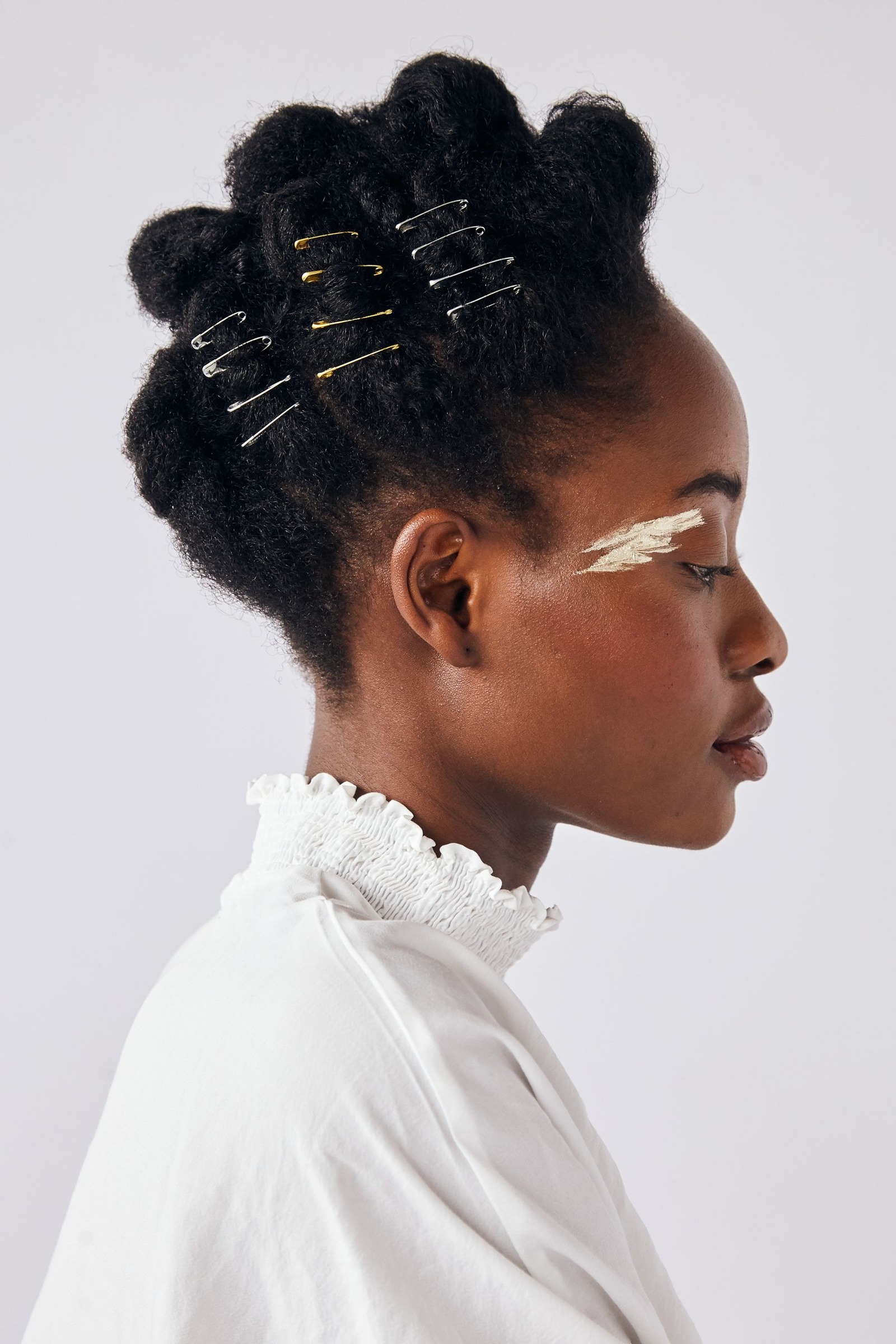 Profile of a woman with hair pins and styled Afro-textured hair