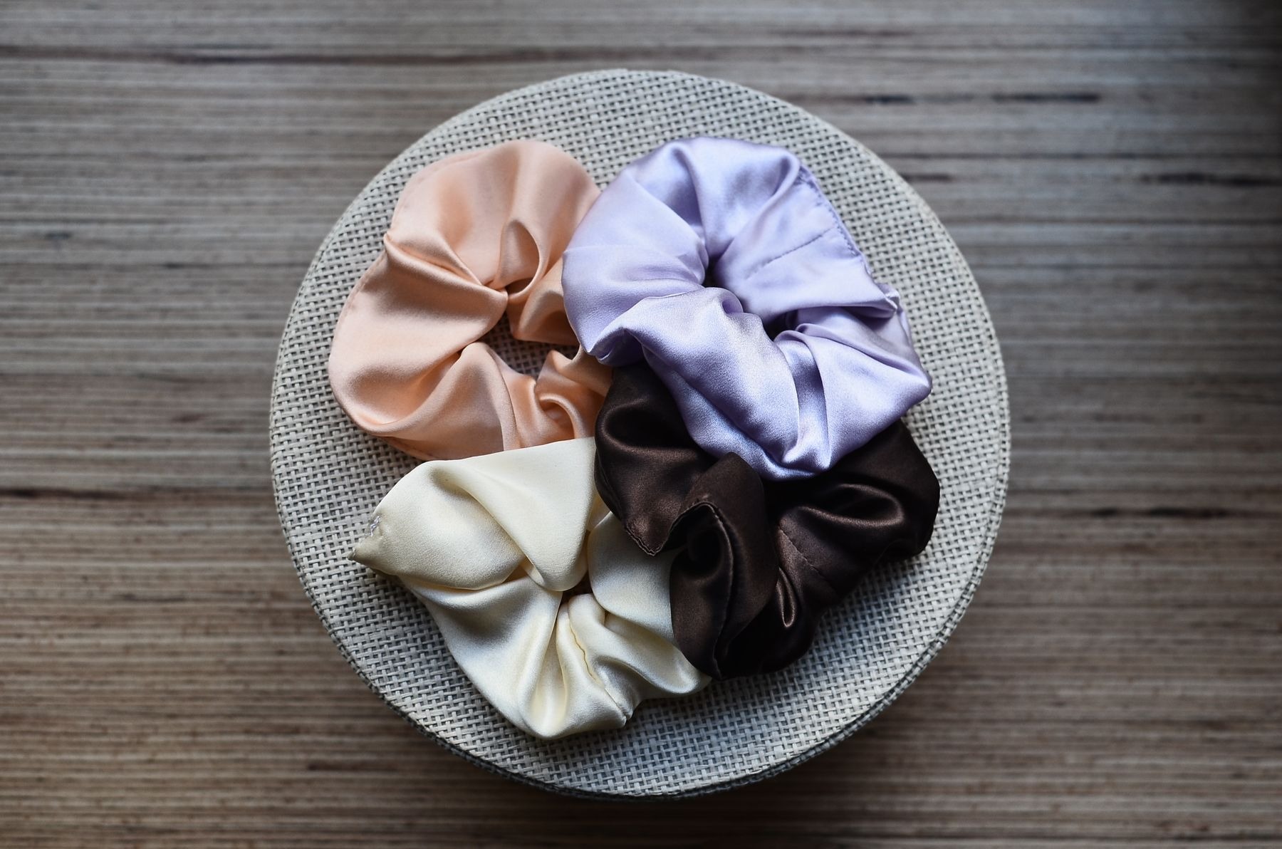 Assorted silky hair ties on a round decorative box on a wooden table