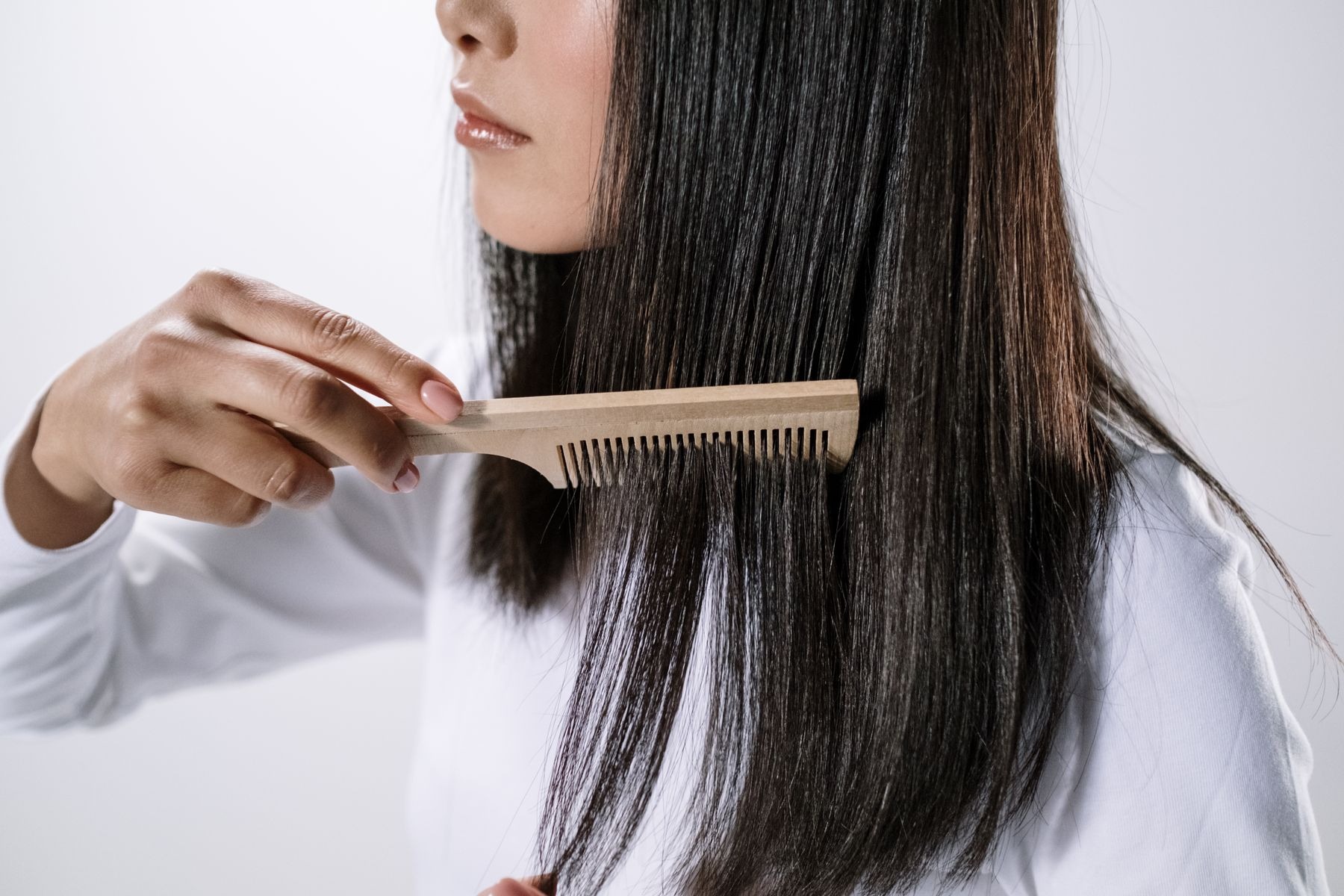 Woman using a wooden comb on her hair indoors
