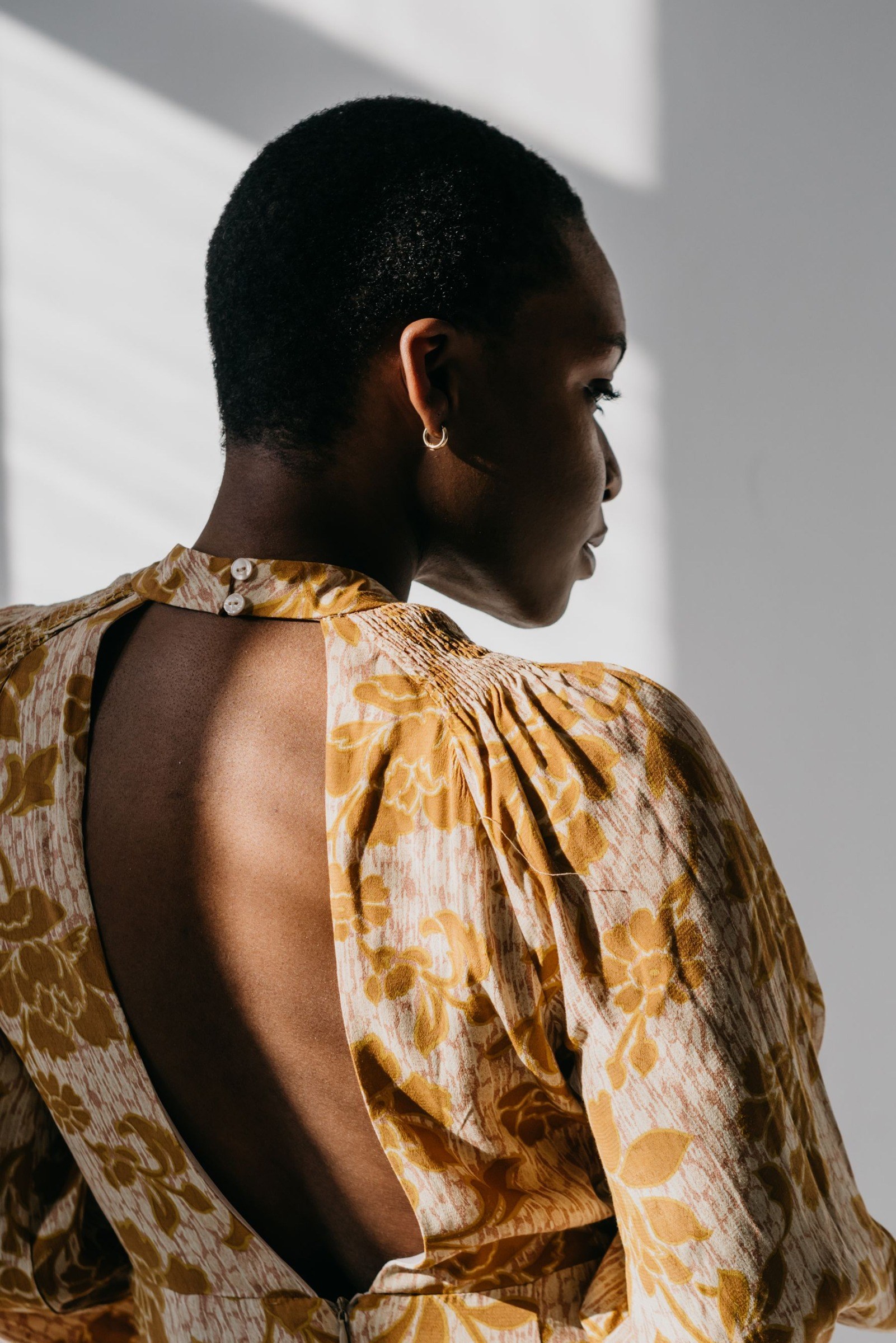 Rear view of short hair above a floral open-back dress in sunlight