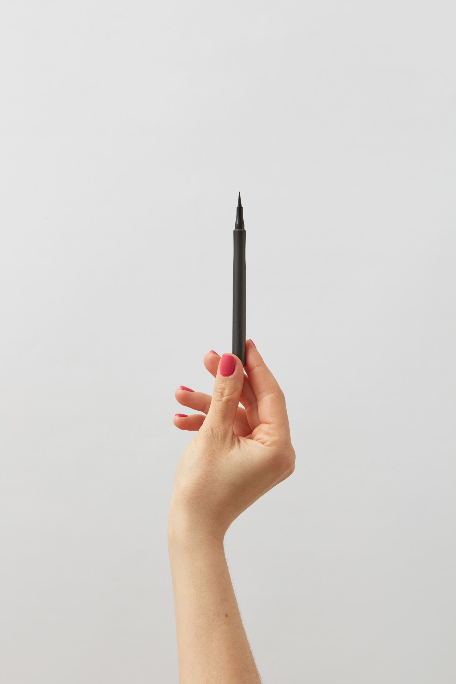 Hand holding a black eyeliner pen against a white background