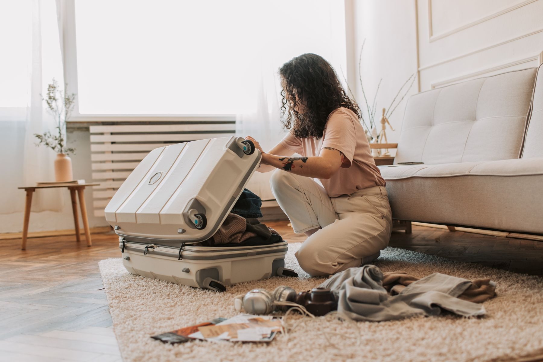 Woman packing clothing into a suitcase in a living room