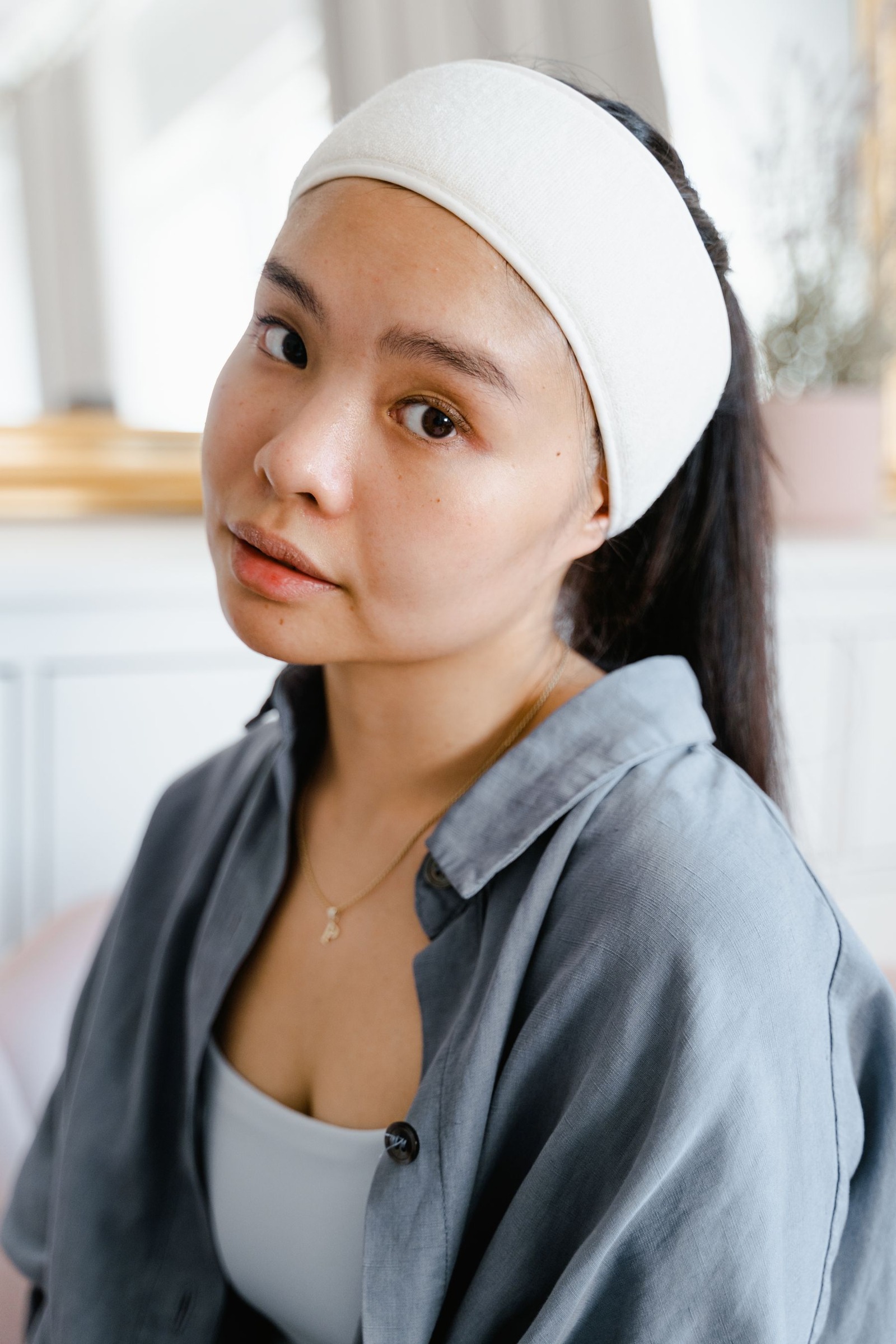 Woman wearing a headband indoors against a neutral background