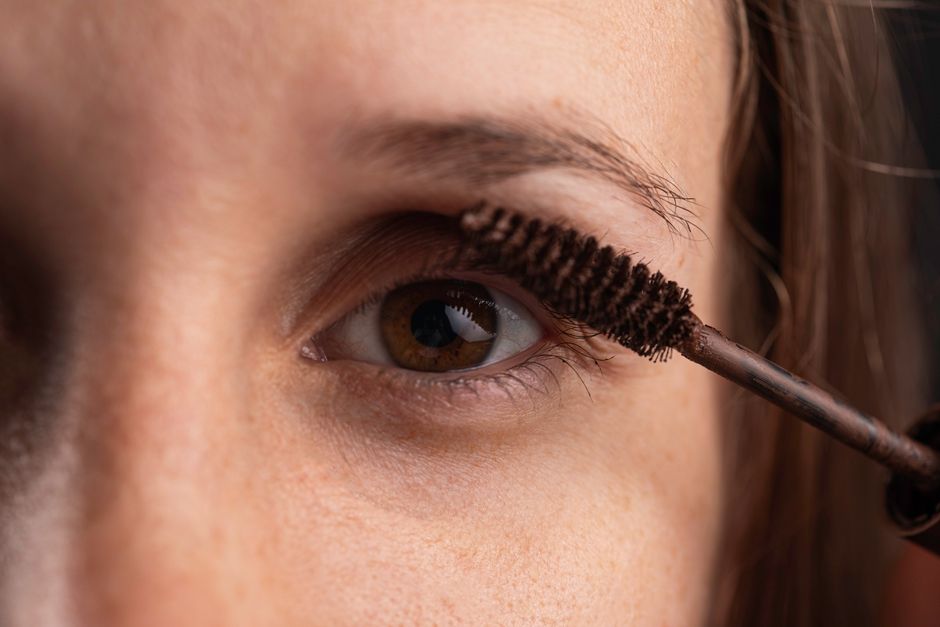 Detailed close-up of an eye with mascara being applied for beauty enhancement.