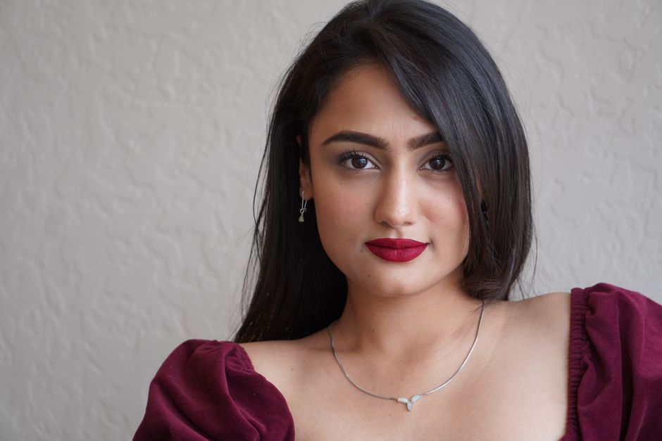 Stylish portrait of a woman in a burgundy dress with bold makeup and elegant jewelry.